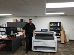 STAT Business Systems expert with KIP wide format copier in Fort Lauderdale office, copier leasing in South Florida.