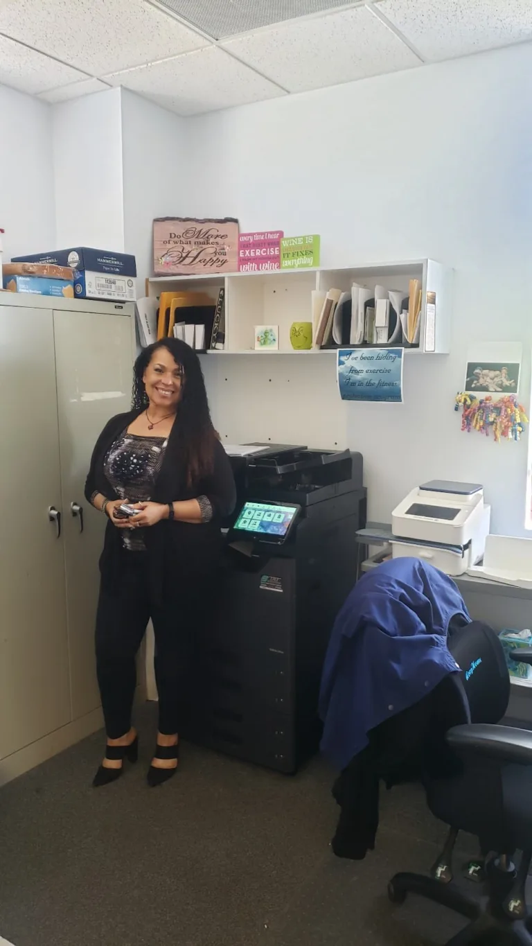 Business professional standing beside a new Kyocera TASKalfa copier in an office setting, smiling proudly