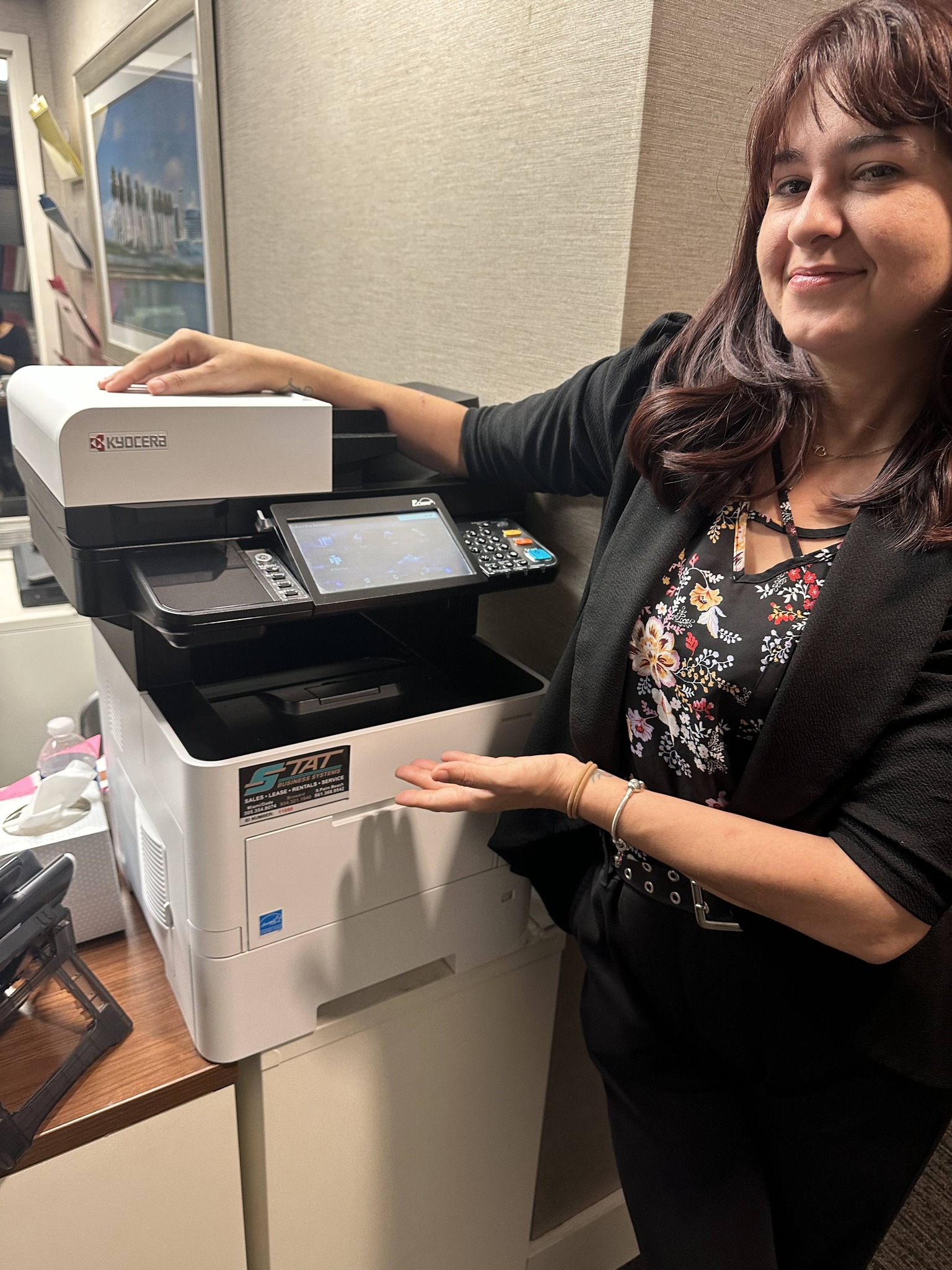Hotel employee showcasing a newly installed Kyocera multifunction printer as part of a 20-year technology partnership with STAT Business Systems.