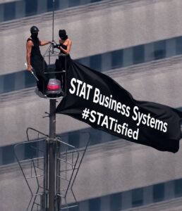 STAT Business Systems STATisfied Banner - STAT Business Systems - STAT Business Systems STAT Business Systems banner displayed high above a city building, representing the company’s goal of helping South Florida customers feel STATisfied with copier leasing and service.