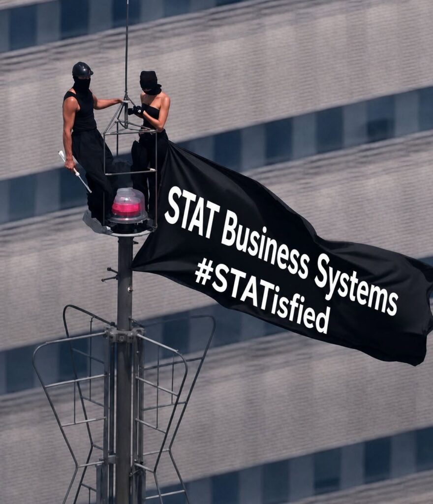STAT Business Systems banner displayed high above a city building, representing the company’s goal of helping South Florida customers feel STATisfied with copier leasing and service.