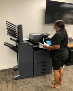 How to Read a Copier Comparison Chart Before You Buy featured image - STAT Business Systems - STAT Business Systems Office employee using a Kyocera color multifunction copier