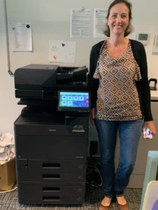 STAT article image Where Should You Put a Shared Office Printer - STAT Business Systems Office employee standing beside a multifunction copier