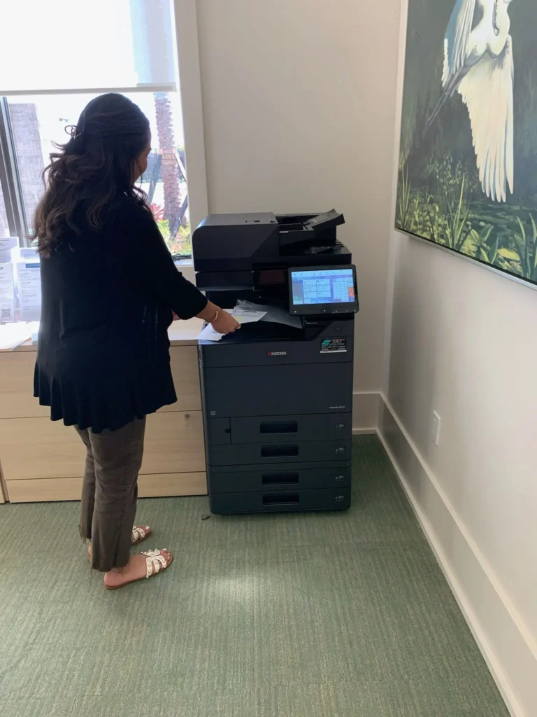 Office employee using a multifunction copier beside a window