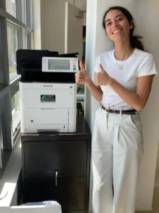 Printer Planning for a New Fort Lauderdale Real-Estate Branch featured image - STAT Business Systems - STAT Business Systems Customer beside a compact Kyocera ECOSYS multifunction printer